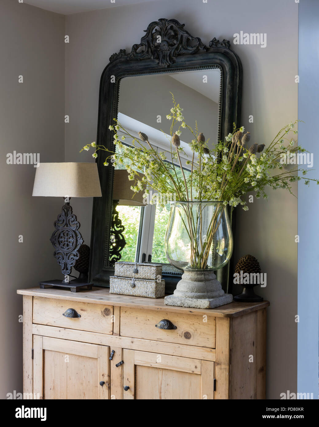 Grand miroir en bois sur la commode avec une lampe de table et grand vase en verre Banque D'Images
