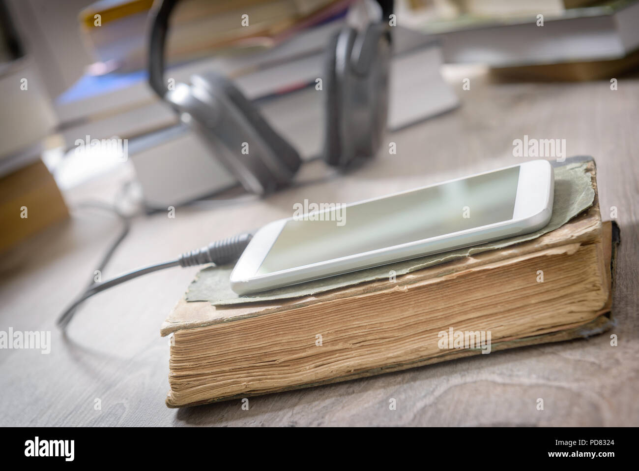 Téléphone intelligent avec un casque et le papier des livres. Concept d'écouter des livres audio. Banque D'Images