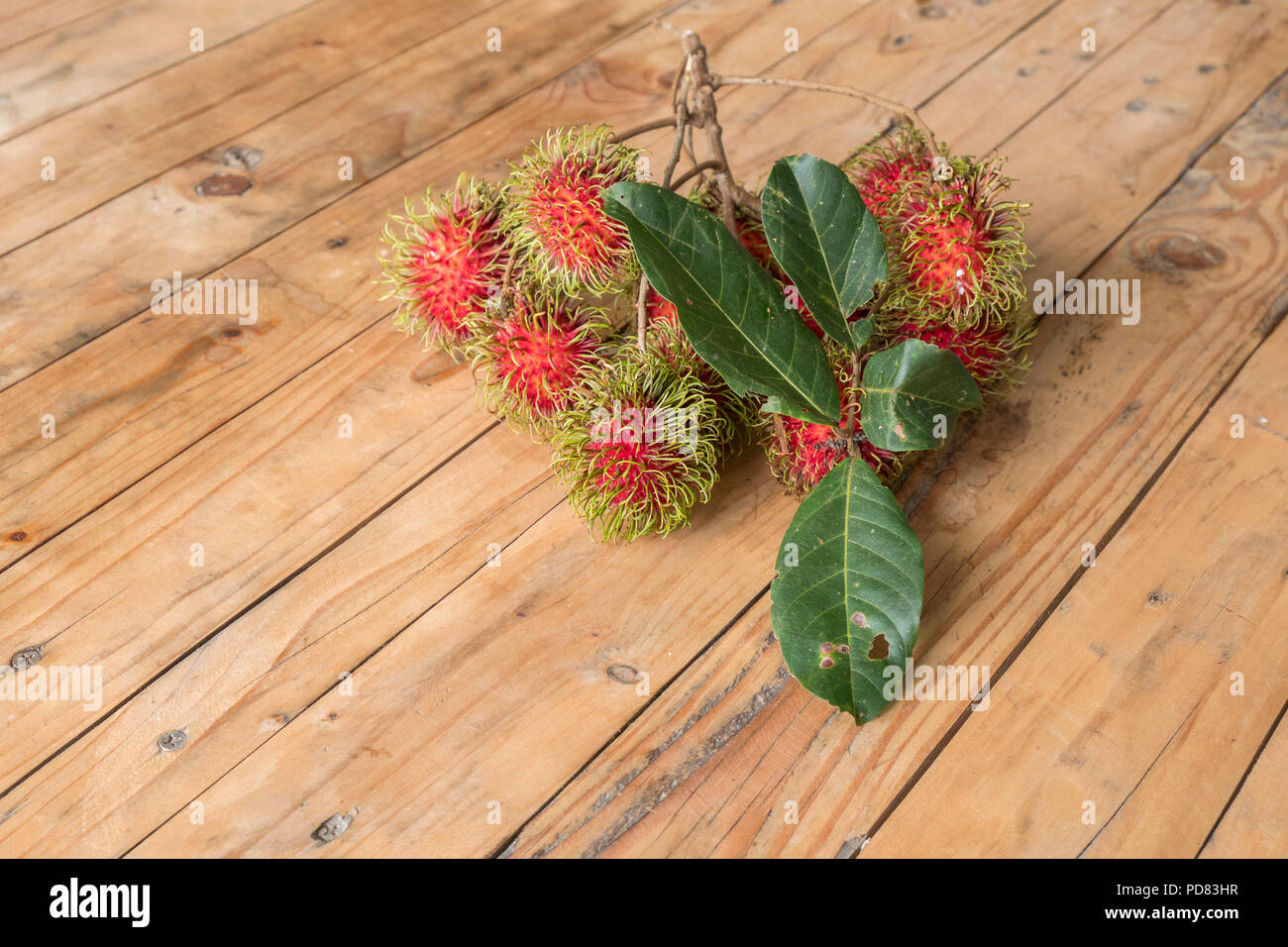 Ramboutan Nephelium lappaceum rouge sur broun conseil. Fruit arbre tropical de la famille des Sapindaceae , native du sud-est asiatique - , cultivé dans de nombreux pays Banque D'Images