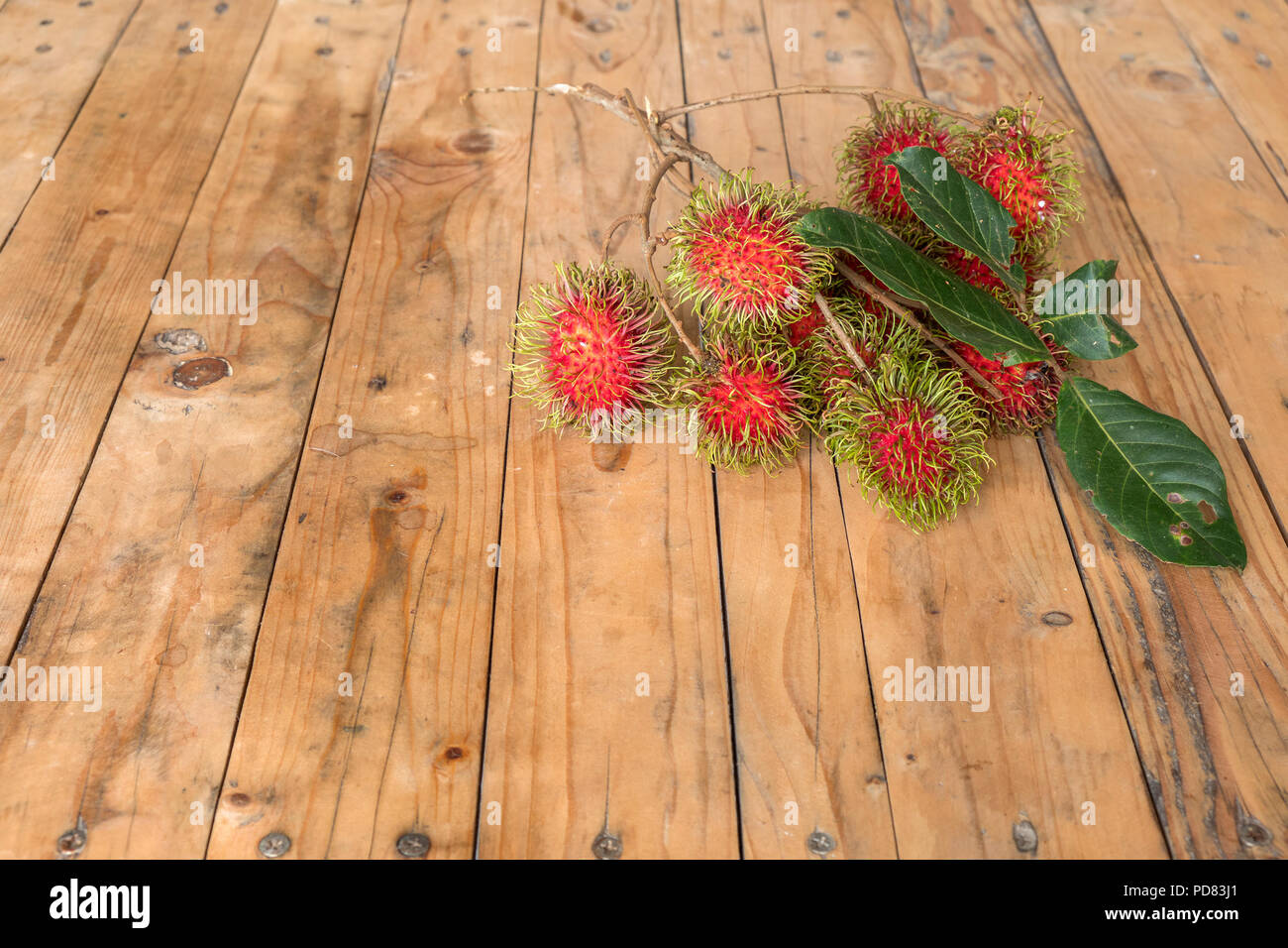 Ramboutan Nephelium lappaceum rouge sur broun conseil. Fruit arbre tropical de la famille des Sapindaceae , native du sud-est asiatique - , cultivé dans de nombreux pays Banque D'Images