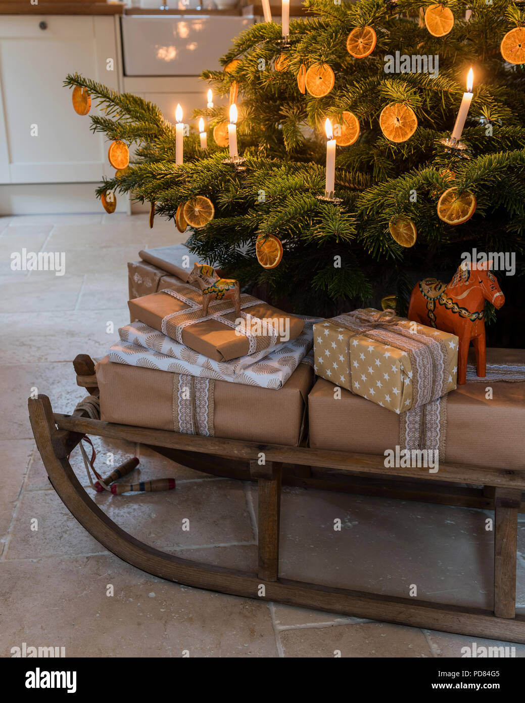 Wrapped presents sur un traîneau en bois en dessous de l'arbre de Noël aux chandelles Banque D'Images
