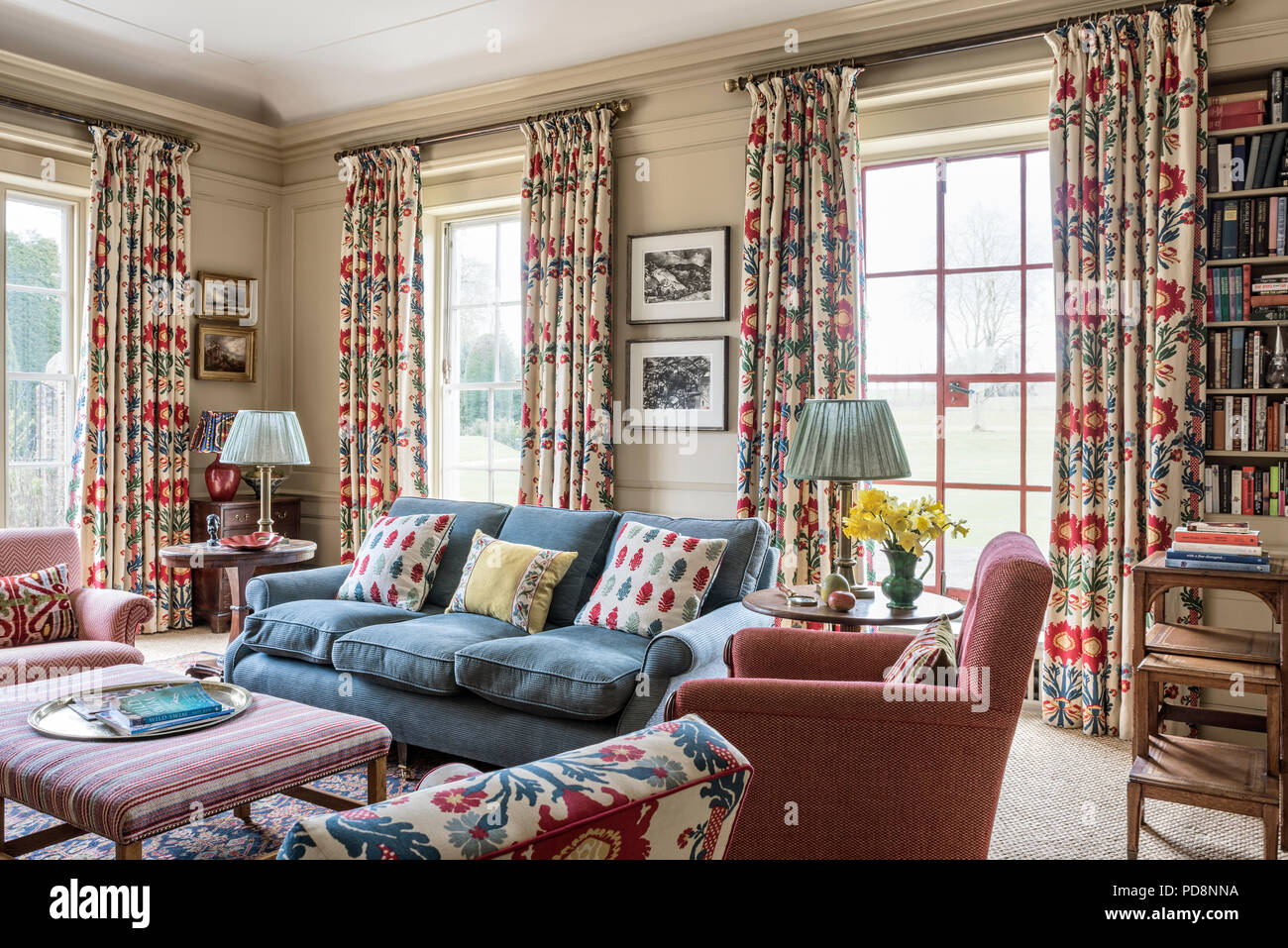 Les rideaux à fleurs jardin portes françaises dans la salle de séjour avec canapé bleu Banque D'Images