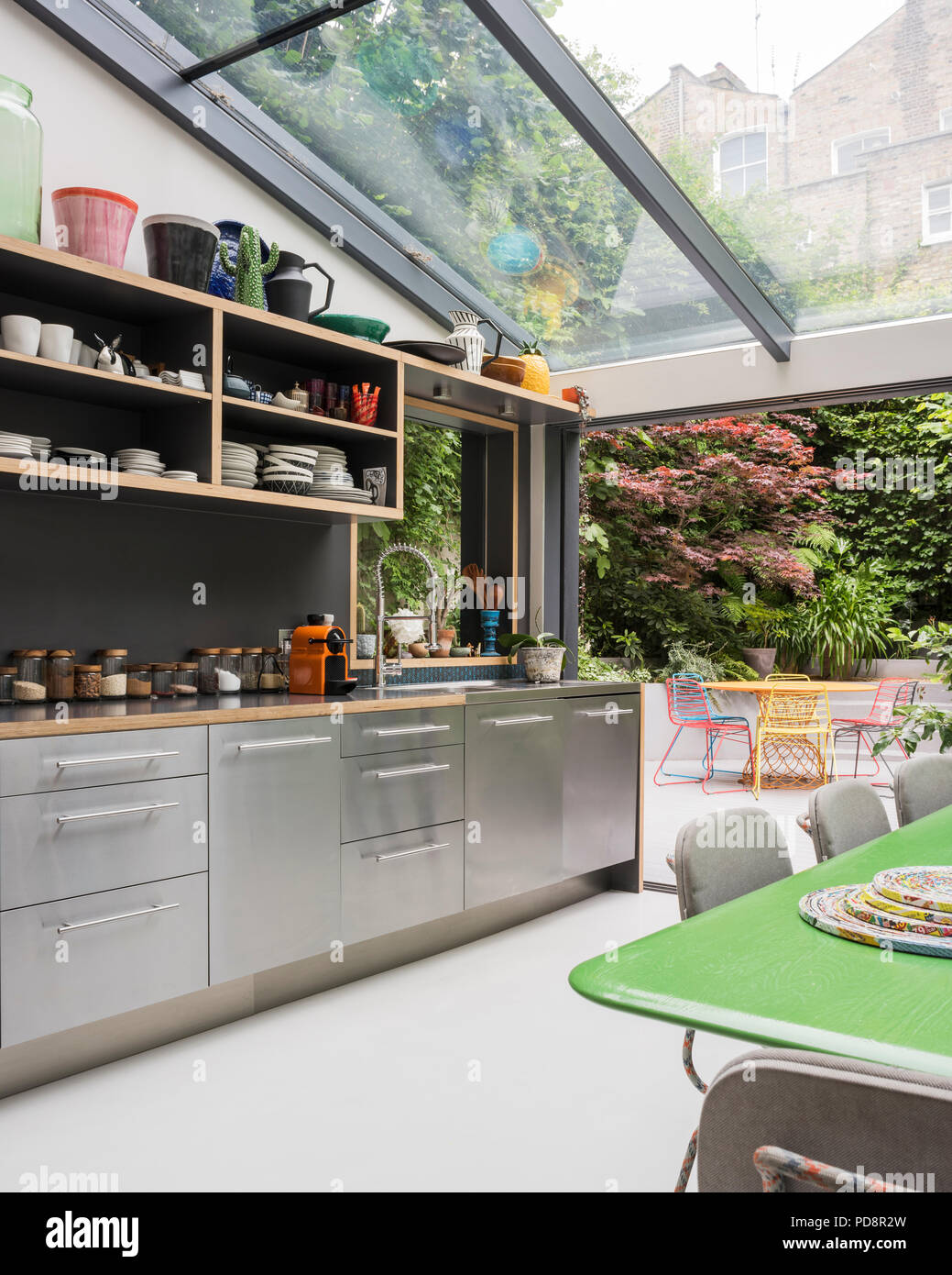 Tableau peint en vert personnalisé par Tom Dixon et de chaises de cuisine en verre Moooi avec terrasse de jardin. Banque D'Images