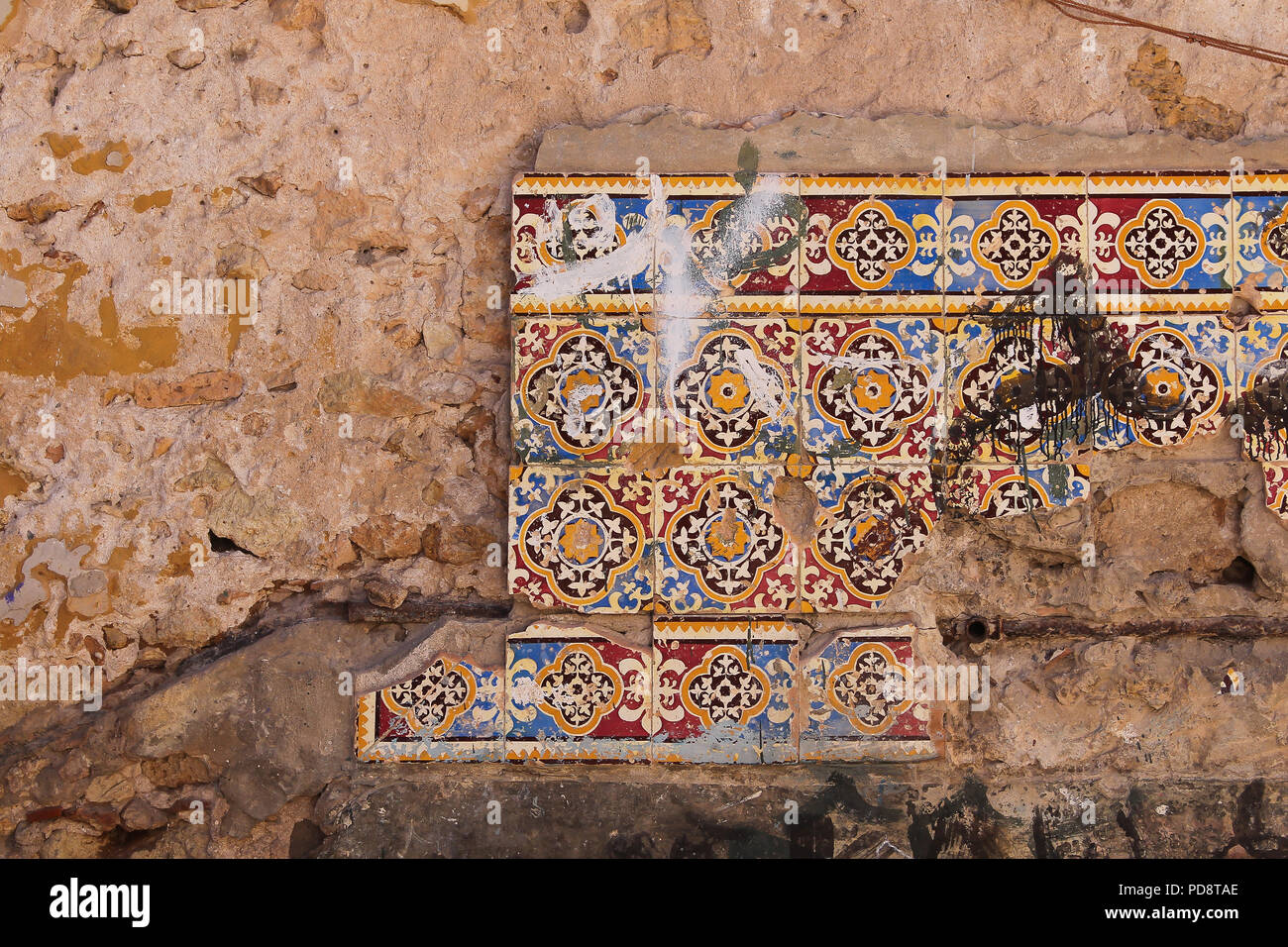 Quatre lignes d'une brisés, les carreaux de céramique traditionnelle sur un mur endommagé d'une vieille maison. El Jadida, Maroc. Banque D'Images