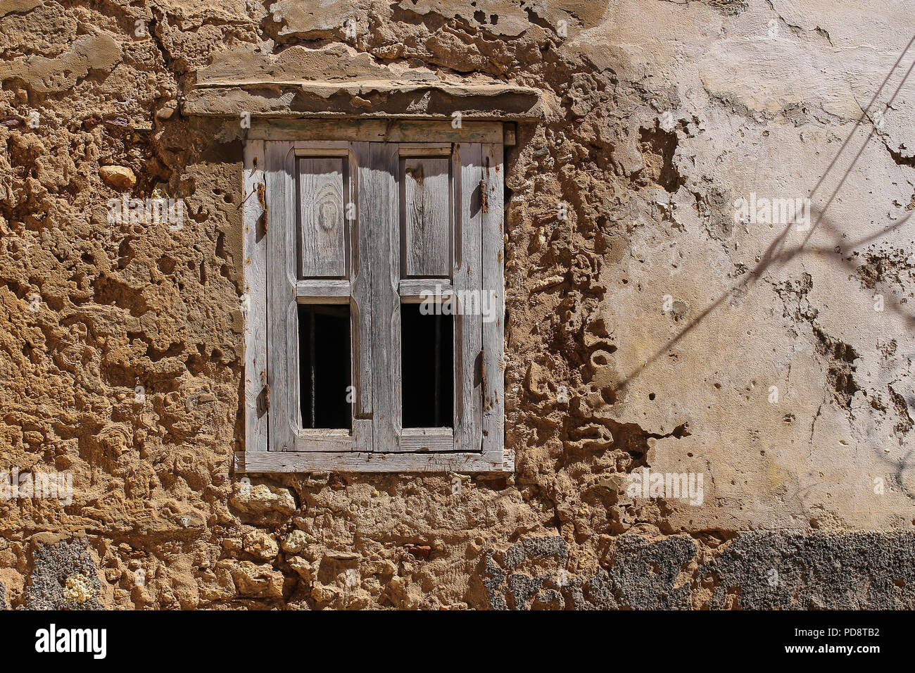Pela façade d'une vieille maison. Fenêtre avec un volet en bois naturel, en partie fragile. El Jadida, Maroc. Banque D'Images