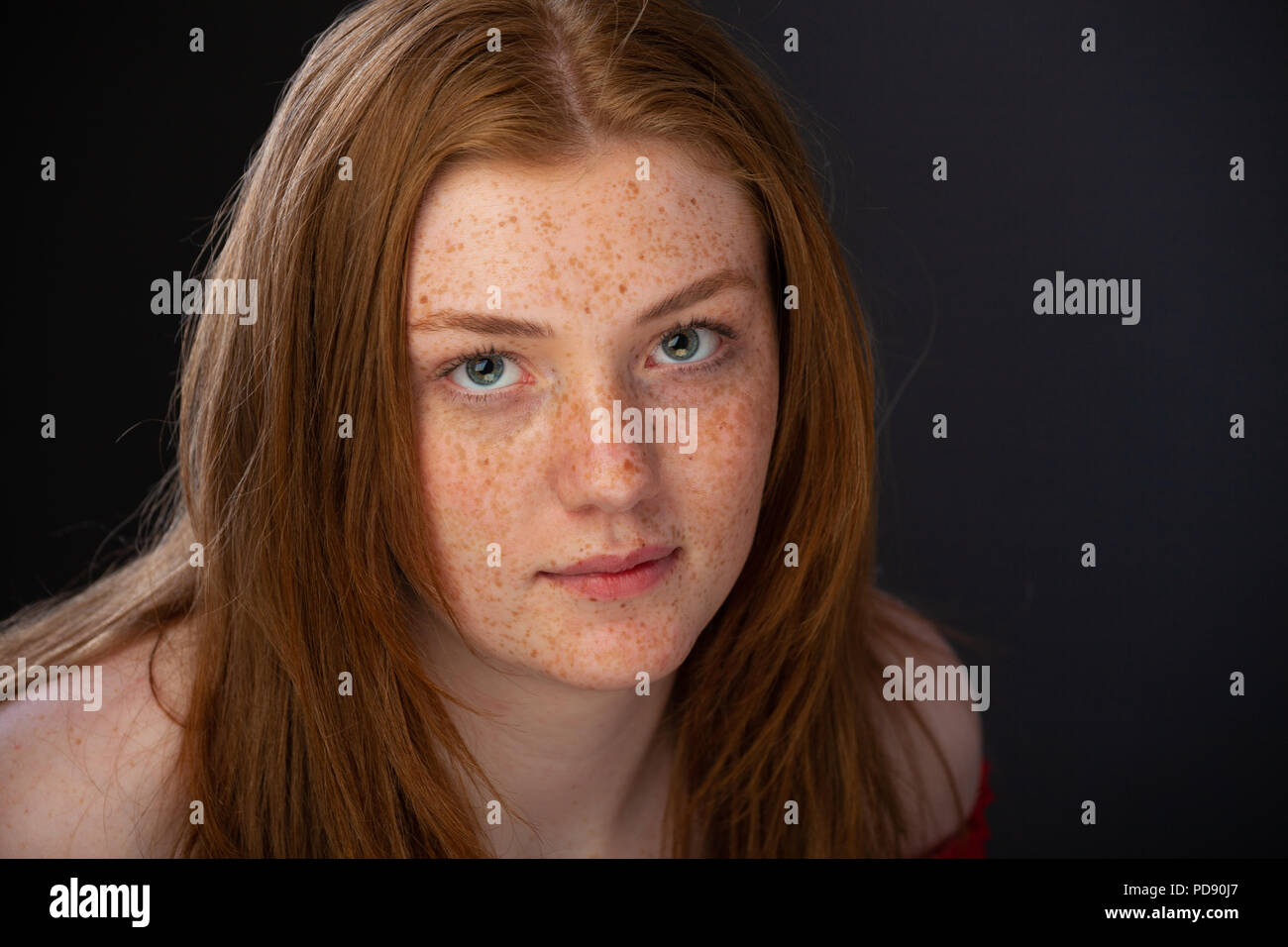 Regardant vers le bas sur une jolie adolescente aux cheveux roux et les taches de rousseur sur un arrière-plan. Banque D'Images