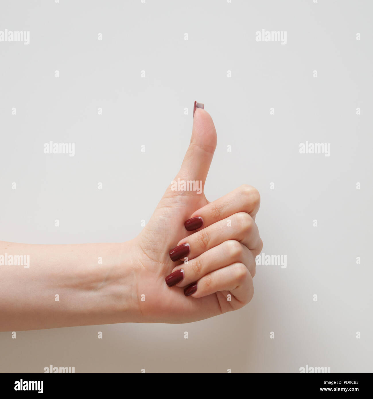 Jeune femme part faire le Thumbs up sign, fond blanc. Banque D'Images