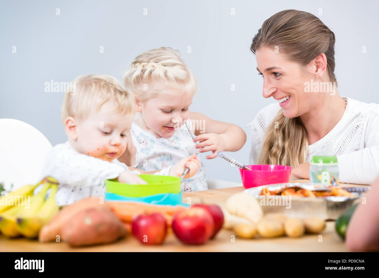 Portrait d'une heureuse mère de deux enfants assis à table Banque D'Images