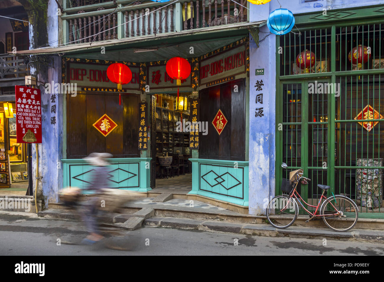 Deux vitrines à Hoi An avec un vélo en stationnement et un cycliste en mouvement. Comme n'importe quel magasin de détail à Hoi An avec des lanternes, etc. Banque D'Images