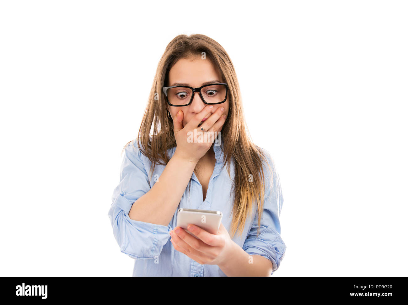 Jeune femme dans les verres à la super surpris et choqué en regardant l'actualité des smartphone et couvrant la bouche Banque D'Images