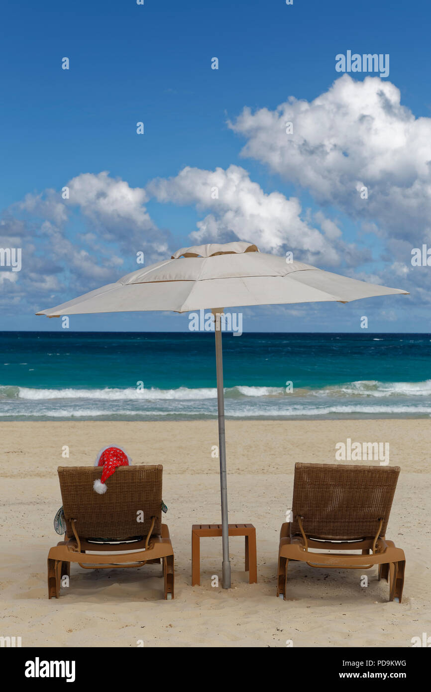 Woman with Santa hat en chaise longue avec parasol sur la plage, Playa Bavaro, Punta Cana, République Dominicaine Banque D'Images