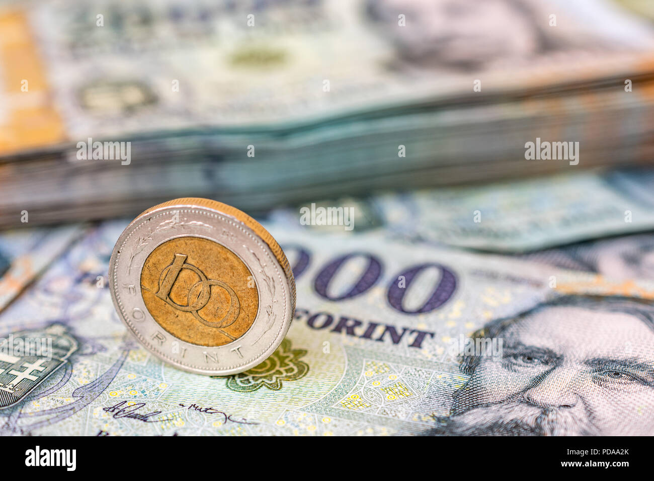 Forint hongrois 100 coin debout sur sa tranche sur 20 000 forint billets avec une pile d'argent dans l'arrière-plan Banque D'Images