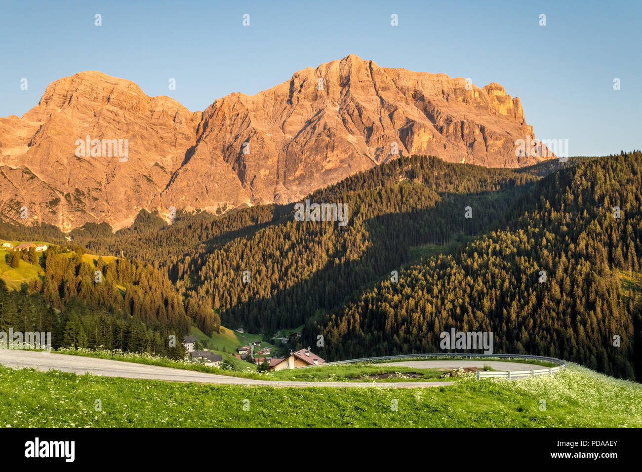 Paysage de montagne pendant le coucher du soleil dans les Dolomites au Tyrol du Sud : des pics de montagne éclairé par le coucher du soleil, route sinueuse sur white flower meadow dans une vallée Banque D'Images