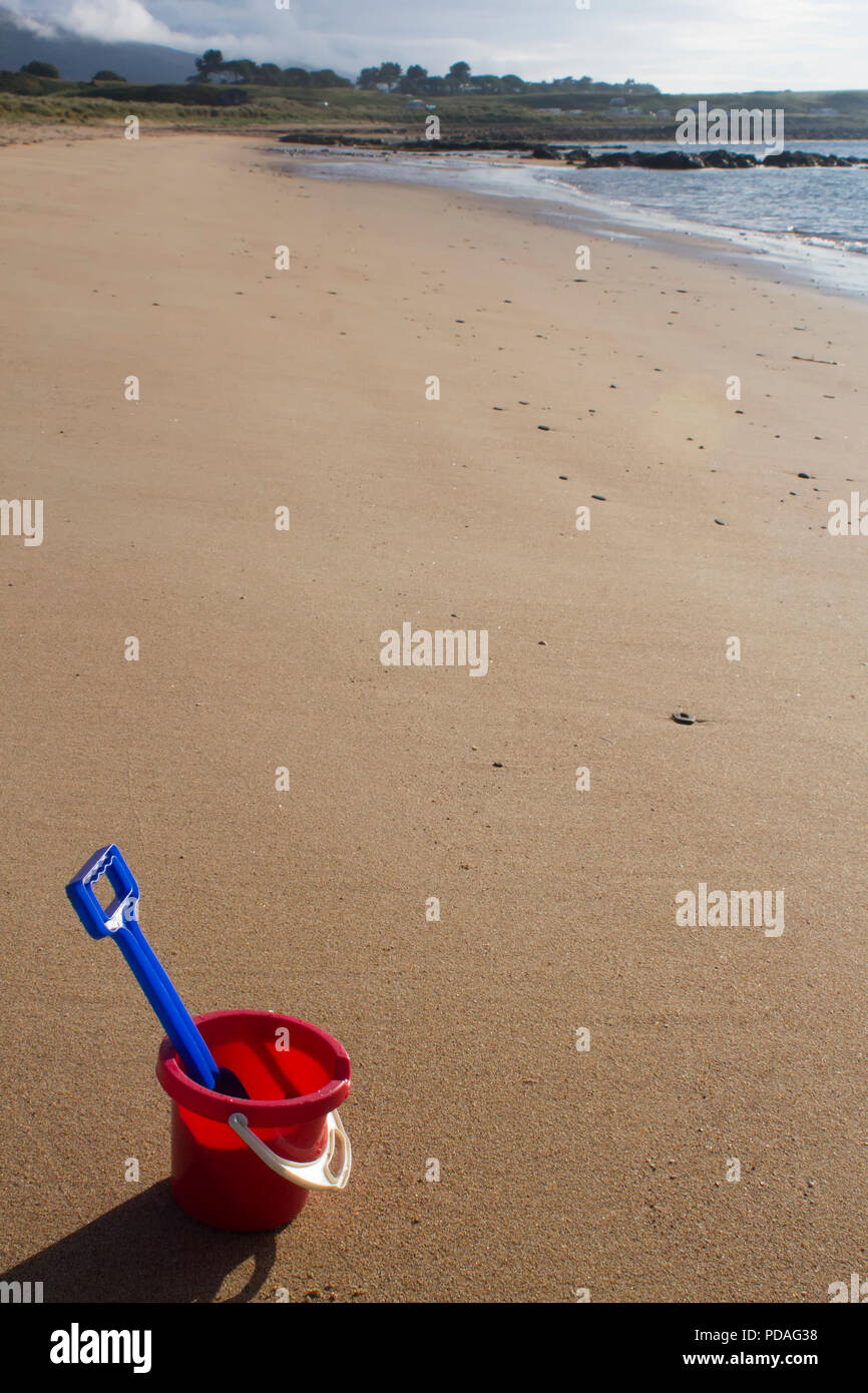 Un seau et chat assis sur une plage de sable au cours d'une journée ensoleillée à Sutherland, Highlands en Écosse. Banque D'Images