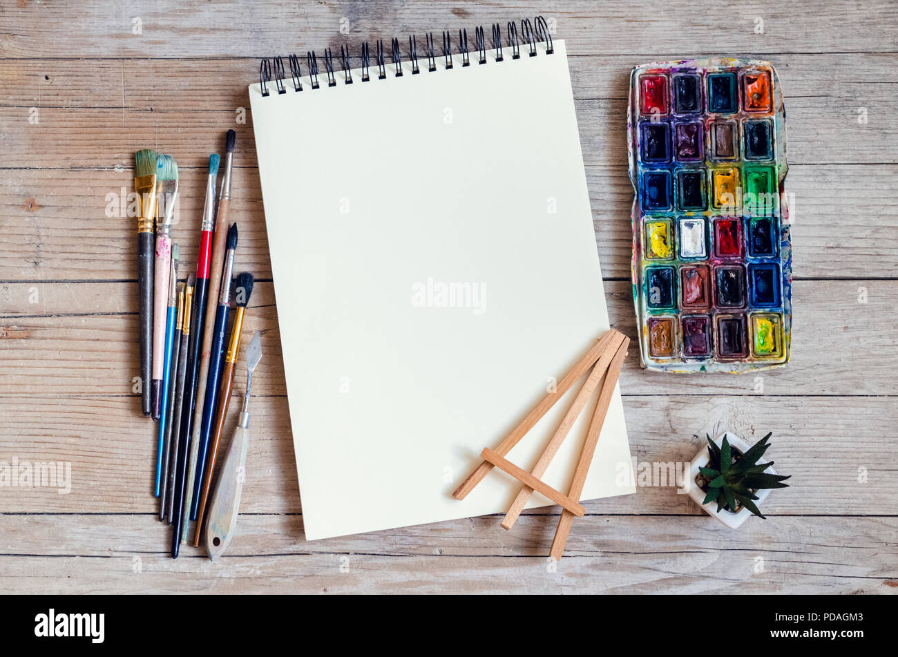 Artiste Créateur de travail télévision lay, immersive. Vue de dessus sur table avec carnet vierge, pinceaux et palettes de colorant. L'Art, atelier, peinture, dessin, Banque D'Images