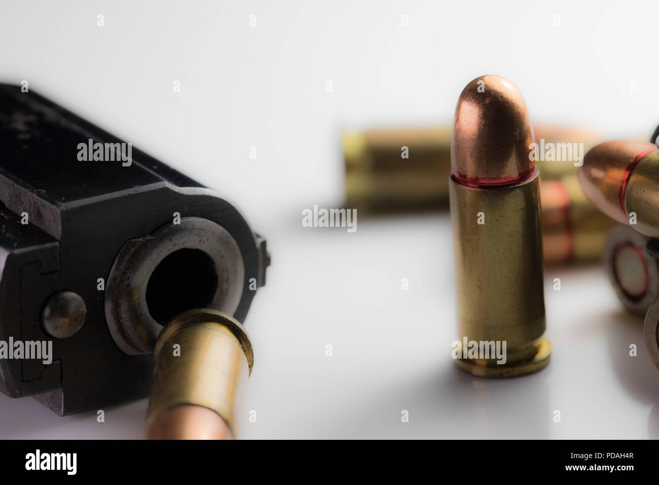 Bullet shells roulant autour d'une arme de poing et clip. Des munitions de calibre 9mm close up déménagement sur un tableau blanc. Banque D'Images