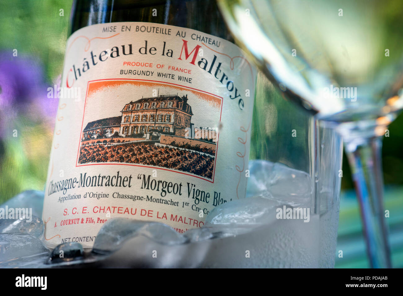 Château de la Maltroye Chassagne-Montrachet 1er cru Bourgogne blanc bouteille de vin dans un seau à glace sur la terrasse ensoleillée avec table en verre de vin France Banque D'Images