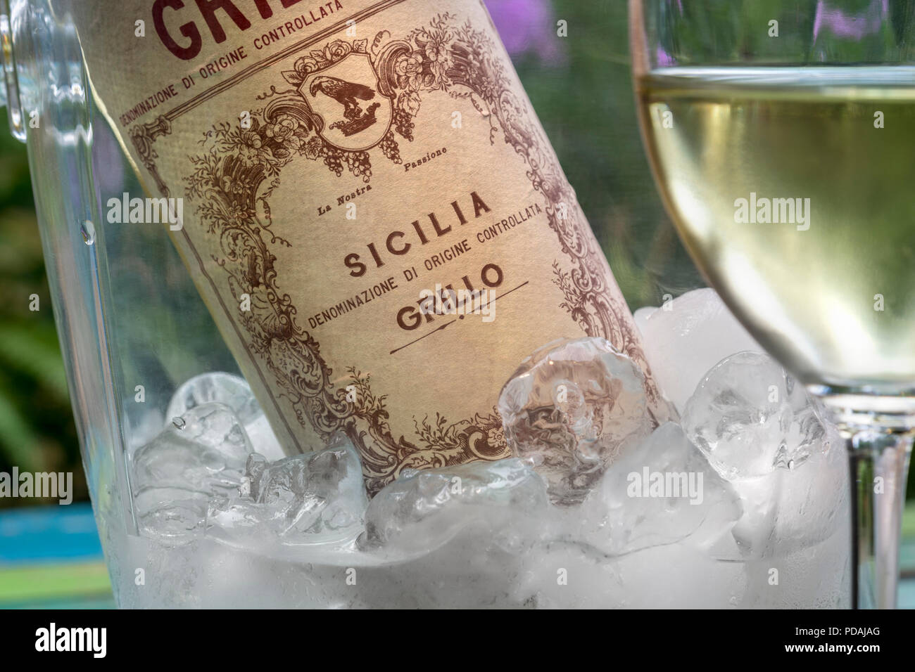 Bouteille de vin de Sicile GRILLO DOC Sicilien Grillo en Vin blanc Vin & verre coulé en premier plan en plein air terrasse jardin floral situation Italie Banque D'Images