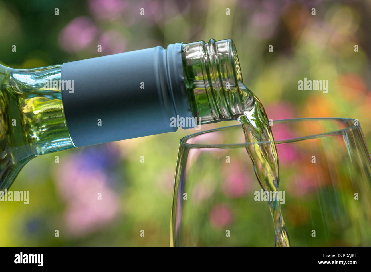 Vin verser en plein air un verre de vin blanc dans un jardin fleuri ensoleillé situation de dégustation Banque D'Images