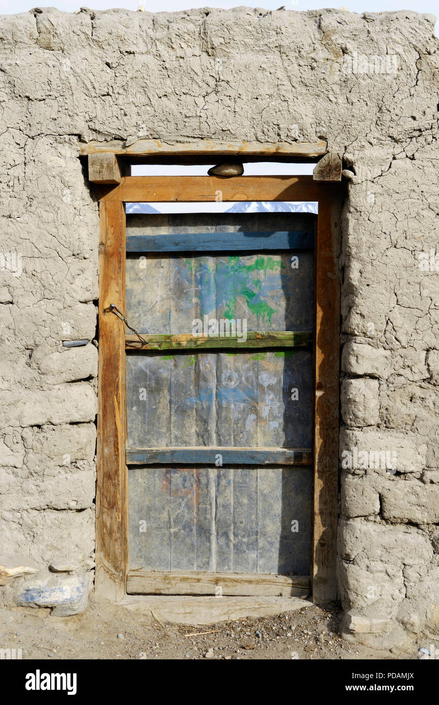 Vieille porte en bois patiné perçant le mur en terre qui encercle la ville ancienne de Lo Manthang, Upper Mustang région, le Népal. Banque D'Images