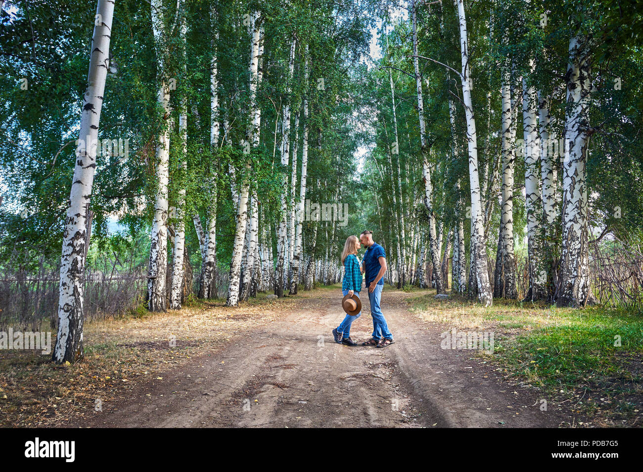 Couple heureux dans les shirts serrant sur la route dans les bois de bouleau, au Kirghizistan. Date romantique dans la forêt. Banque D'Images