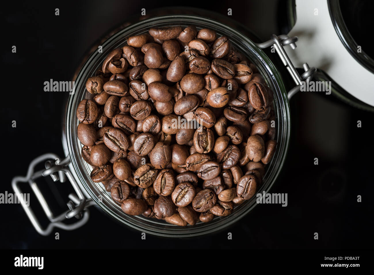 Les grains de café torréfié dans clip top Pot de rangement (vue de dessus sur fond noir Banque D'Images