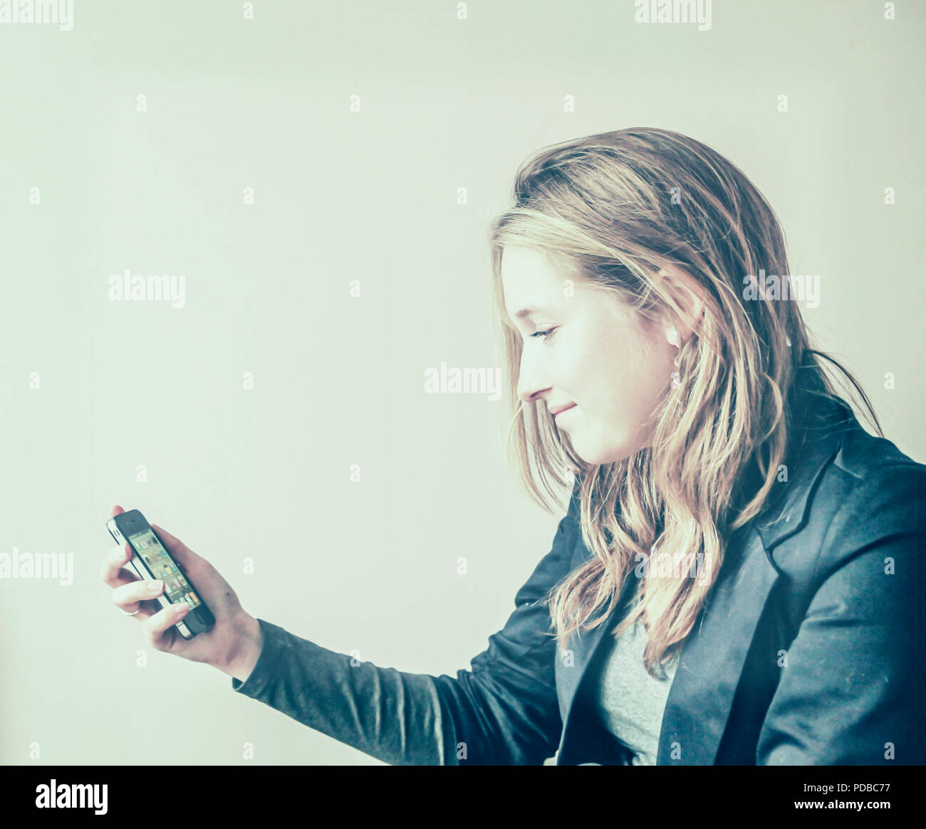 Jolie jeune femme à la recherche d'un sourire à son téléphone cellulaire à écran tactile Banque D'Images