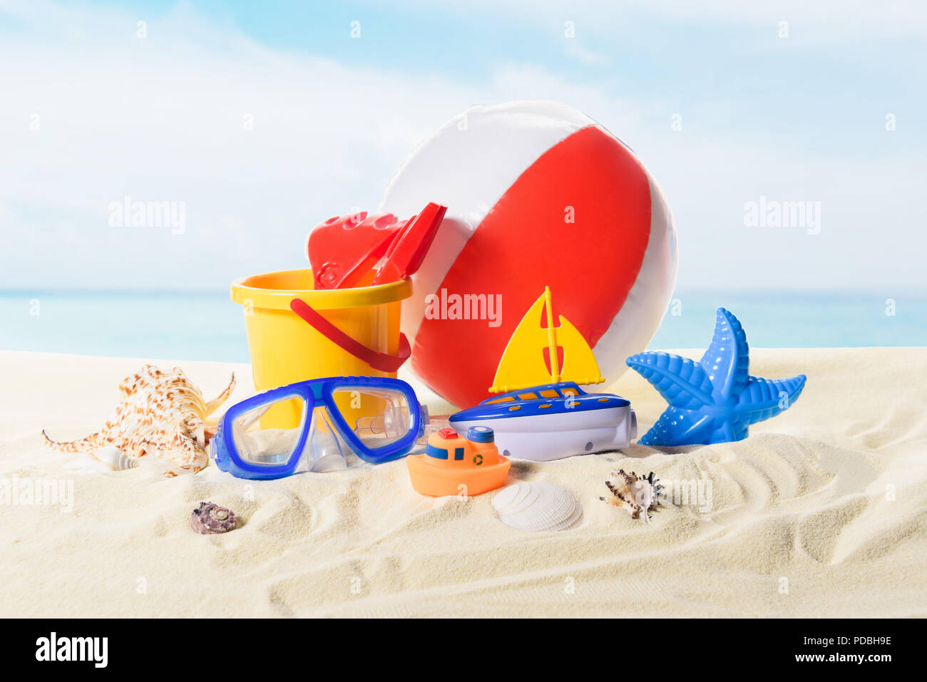 Ballon de plage et des jouets dans le sable sur fond de ciel bleu Banque D'Images