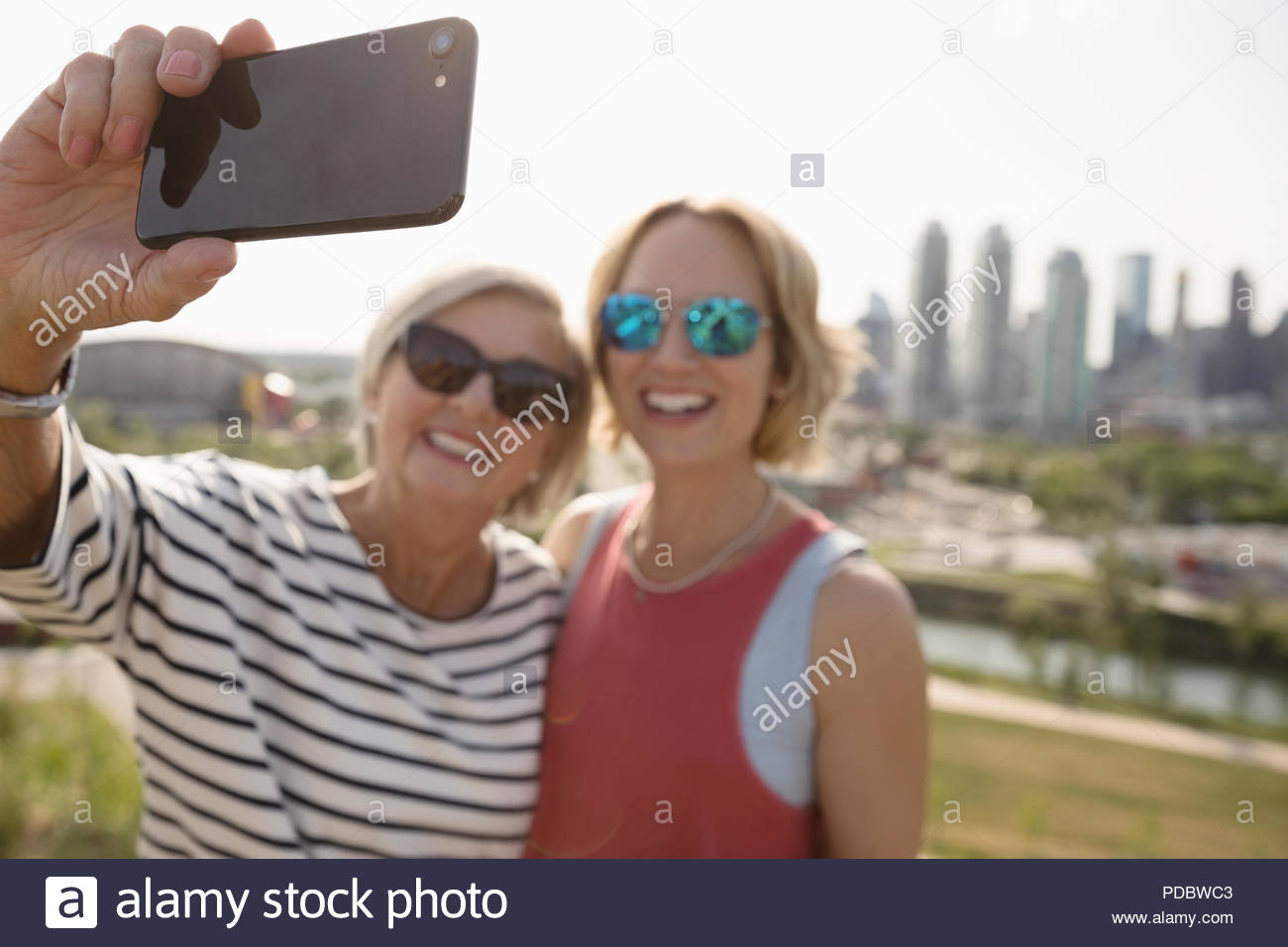 Smiling mother and daughter prenant en selfies parc urbain ensoleillé Banque D'Images