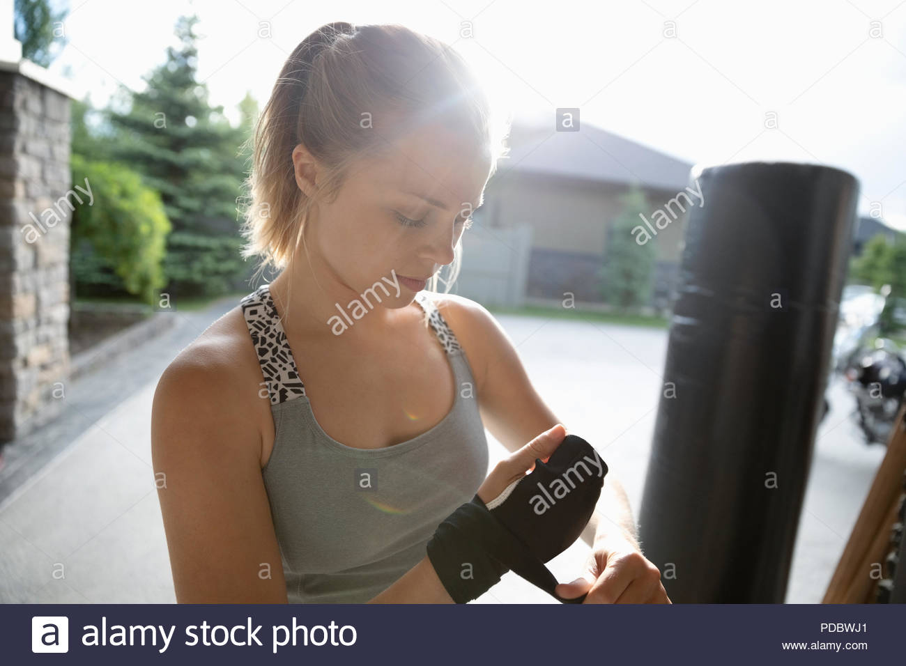 Jeune femme pratiquant les arts martiaux, serrage poignet wrap sunny driveway Banque D'Images