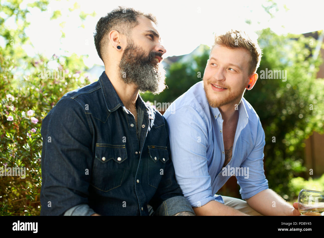 Homme gay couple talking in garden Banque D'Images
