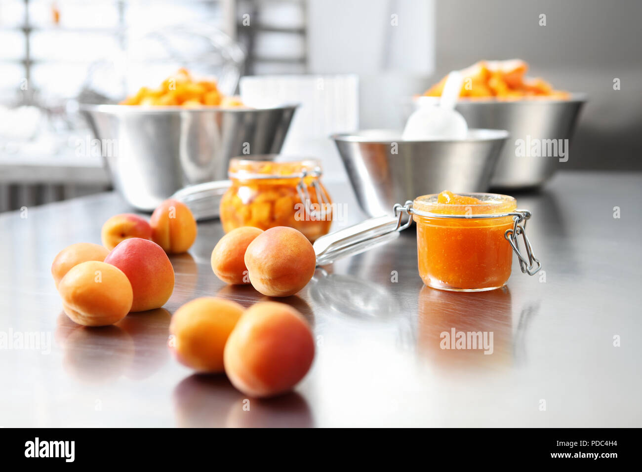 À partir de la confiture d'abricots dans un bocal de verre sur une surface en acier inoxydable poli en pâtisserie plan Banque D'Images