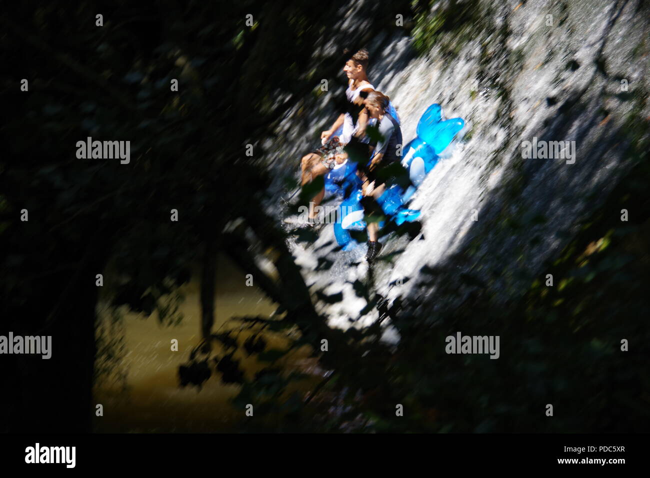 Les adolescents en glissant sur une cascade de béton sur pneumatiques pendant une vague de chaleur. Les adieux du parc Riverside, Sidmouth, l'est du Devon, Royaume-Uni. Août, 2018. Banque D'Images