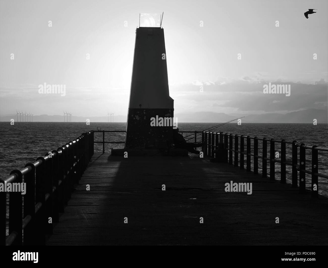 Le soleil derrière la balise de navigation et d'un pêcheur de la mer, le port de Bristol, Cumbria, Royaume-Uni Banque D'Images