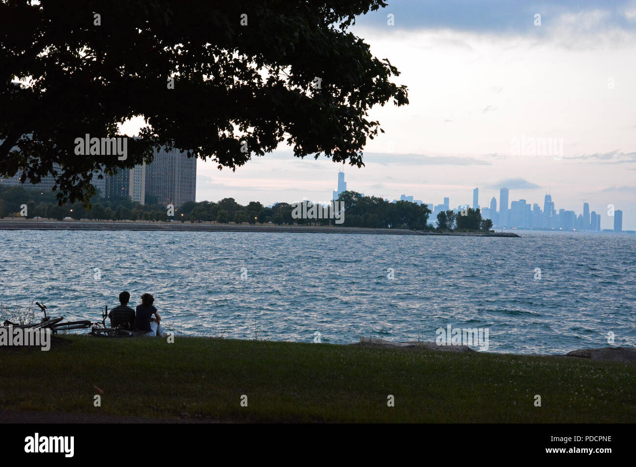 Un couple regarde le soleil se coucher à Promontory Point dans Hyde Park avec l'horizon de Chicago à l'horizon. Banque D'Images
