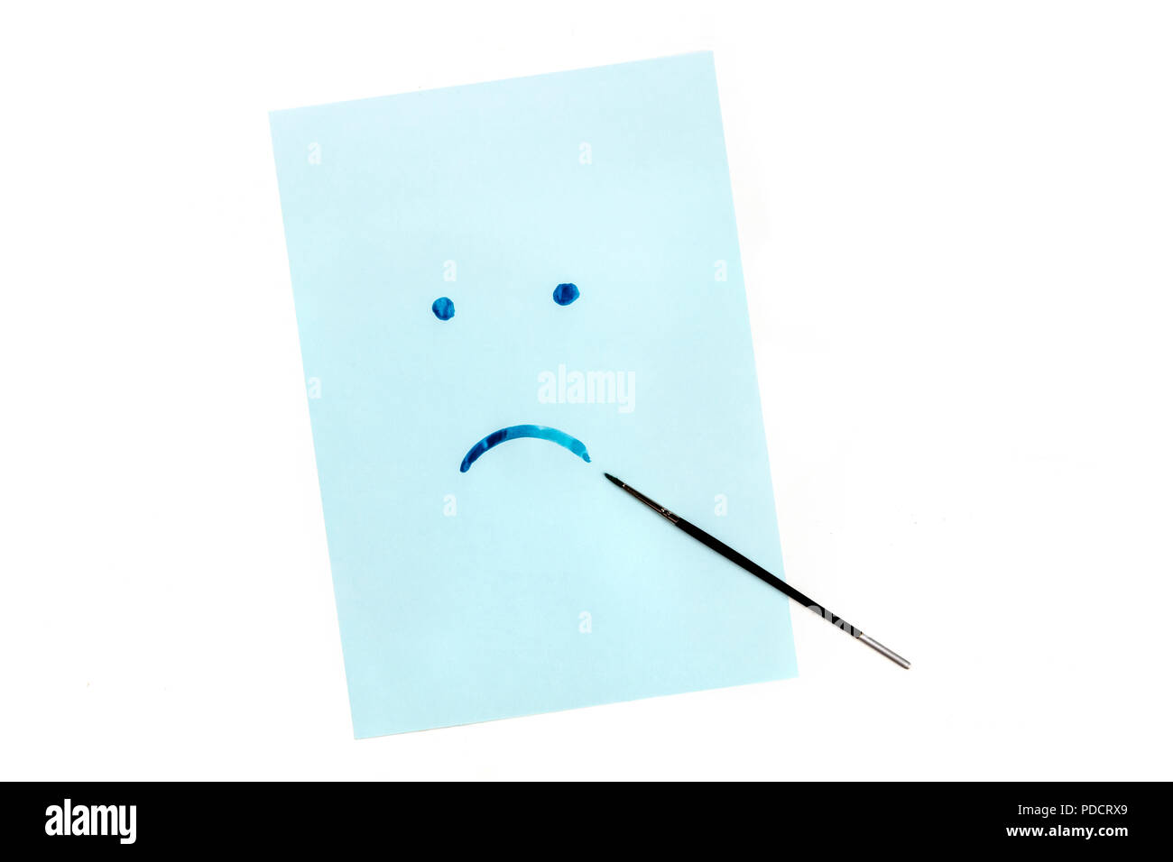 Bleu, une photo prise à la verticale d'un triste visage peint à la main sur du papier bleu à l'aquarelle, la dépression, concept with copy space Banque D'Images