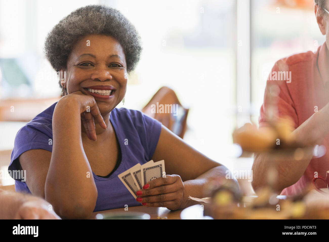 Portrait souriant, confiant senior woman playing cards dans community centre Banque D'Images