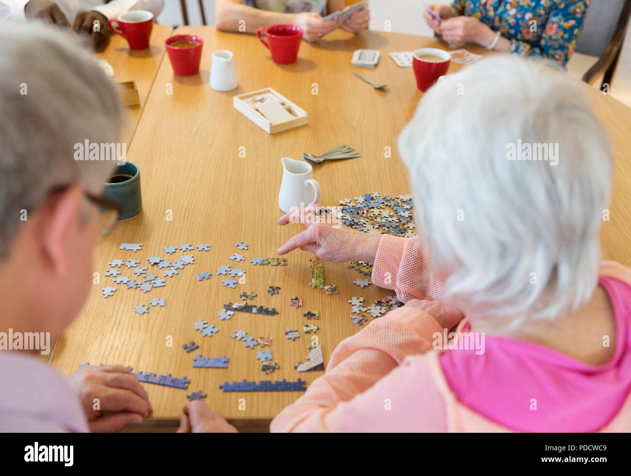 Senior friends assemblage jigsaw puzzle at table in community centre Banque D'Images