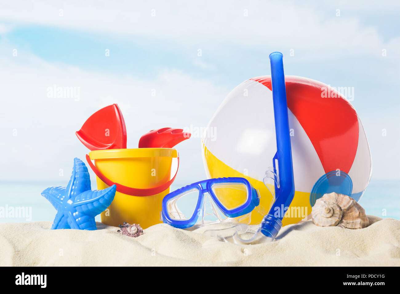 Masque de plongée avec ballon de plage et des jouets dans le sable sur fond de ciel bleu Banque D'Images