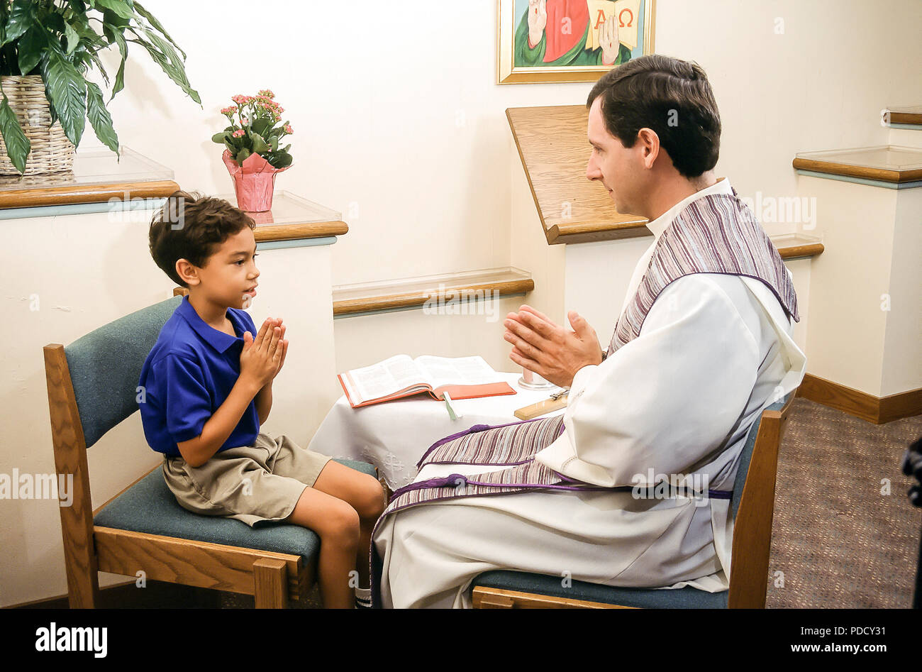 Jeune garçon avec prêtre dans la réconciliation M. © Myrleen ....Pearson Ferguson Cate Banque D'Images