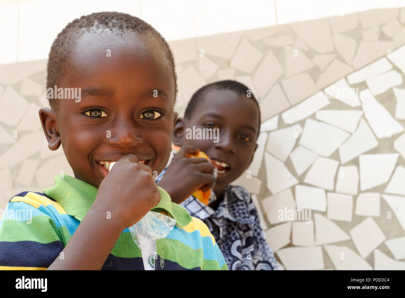 Sénégal, Afrique - 24 avril 2016 : deux inconnus enfants sénégalais aux yeux brillants de manger des collations au cours d'une visite dans leur village. Banque D'Images