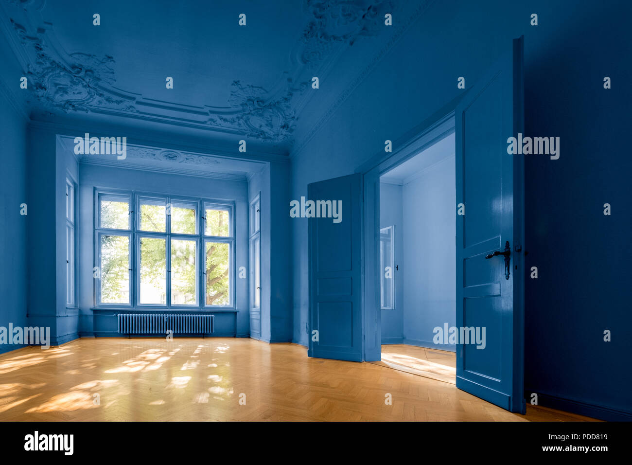 Salle vide dans immeuble ancien avec parquet et murs peints en bleu - Banque D'Images