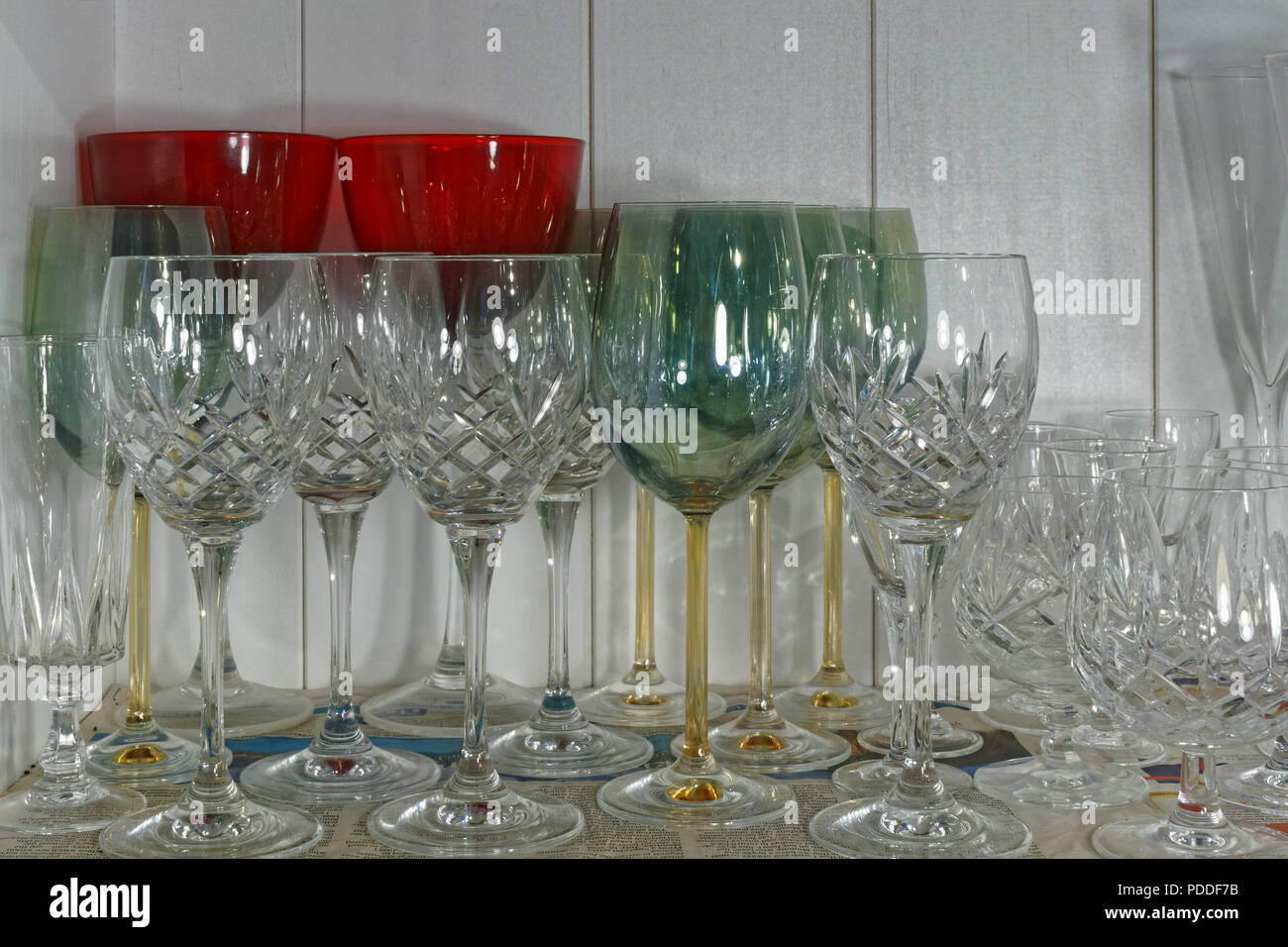 Verres à vin en cristal de différentes formes et tailles debout sur une feuille de journal sur une étagère de rangement Banque D'Images