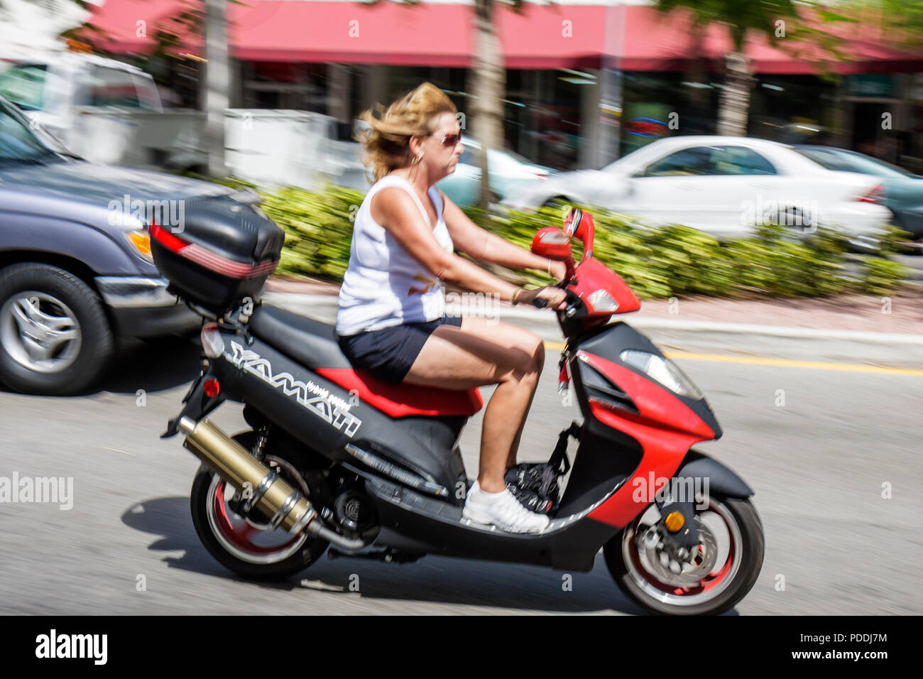 Miami Beach Florida,Washington Avenue,adultes femme femme femme femme dame,rouge,scooter de moteur trottinettes,transport alternatif,sans casque,non sécuritaire Banque D'Images