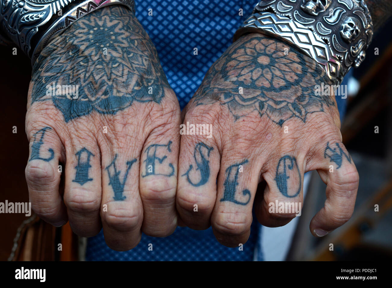 Un homme avec "Live Slow' tatoué sur ses doigts sur les deux mains. Banque D'Images