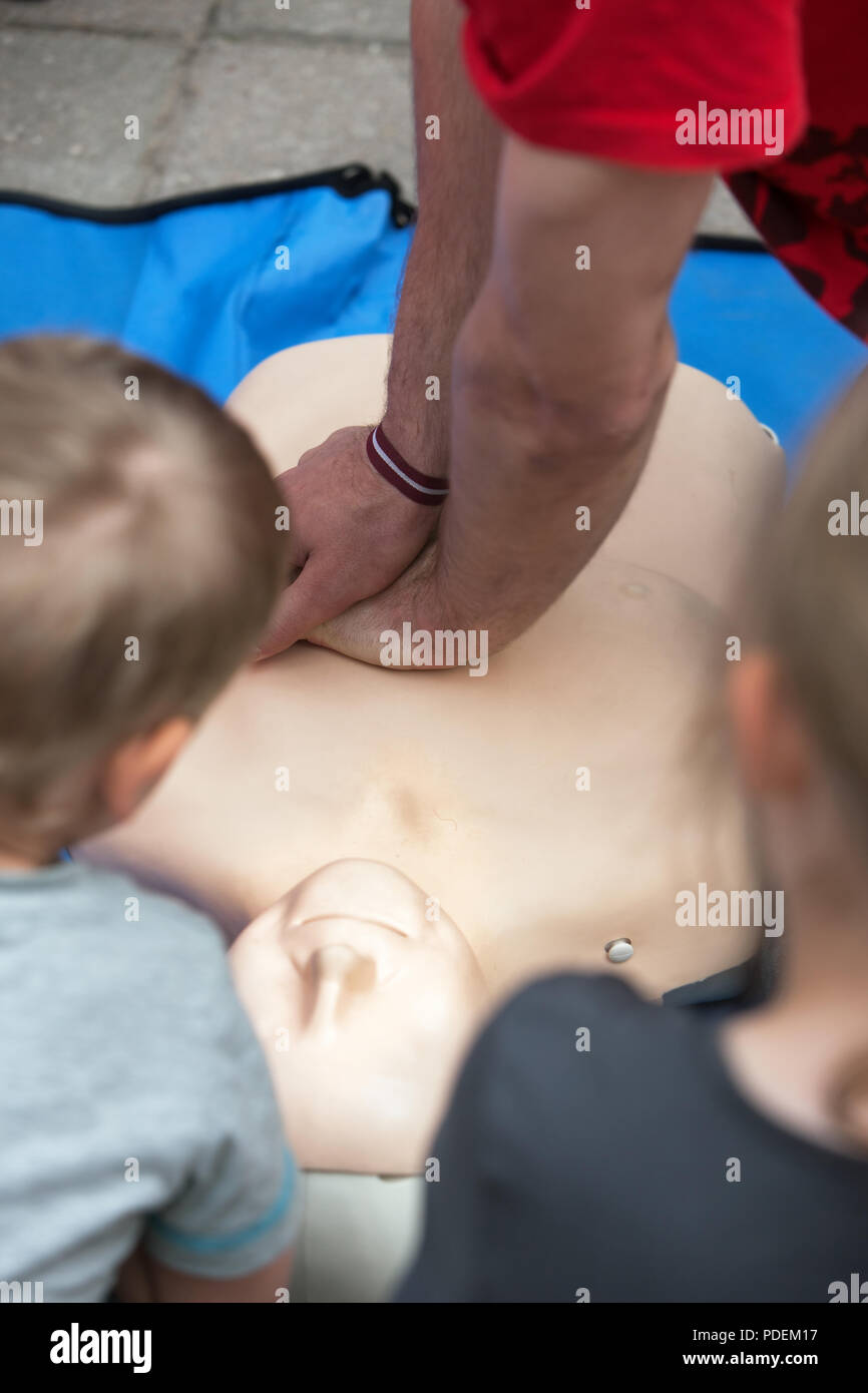 Man doing RCP sur un mannequin pour enseigner deux enfants Banque D'Images