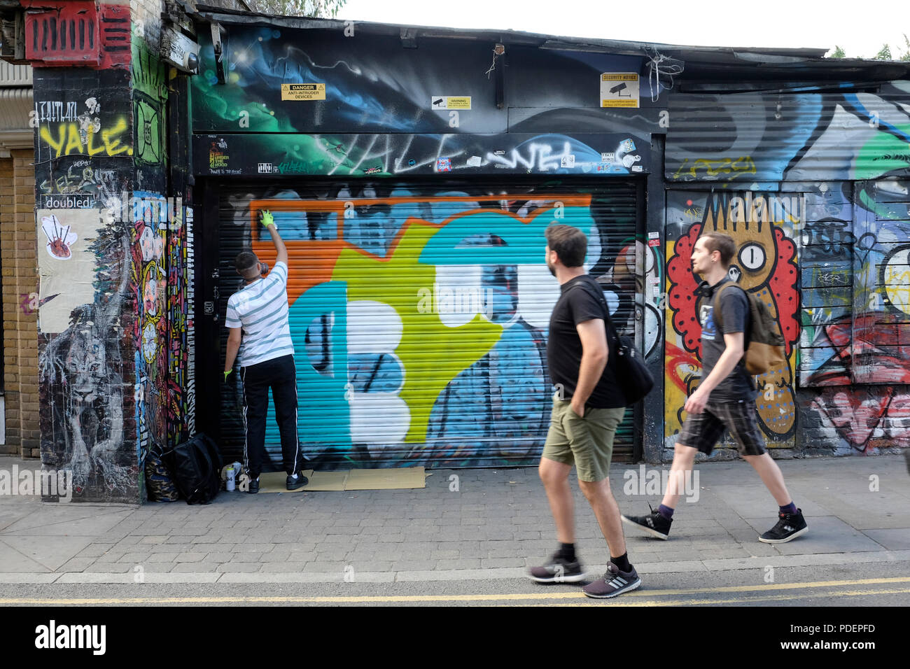 Un graffiti artiste travaille sur une fresque à Brick Lane, London Banque D'Images