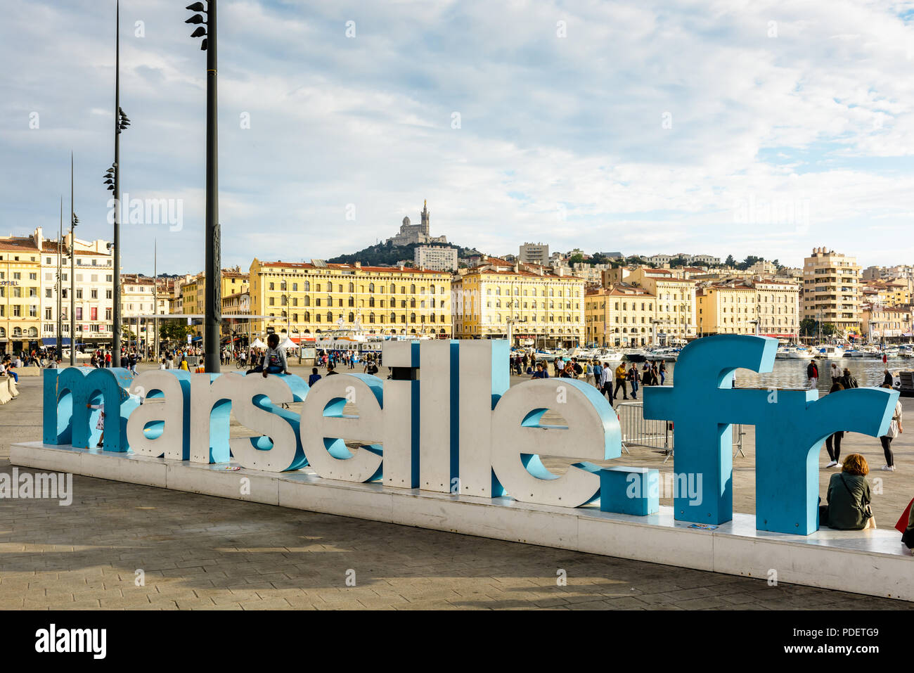 Le Vieux Port de Marseille avec l'adresse du site web de la ville 'marseille.fr' dans de grandes lettres 3D et la Basilique de Notre-Dame de la Garde sur la colline. Banque D'Images