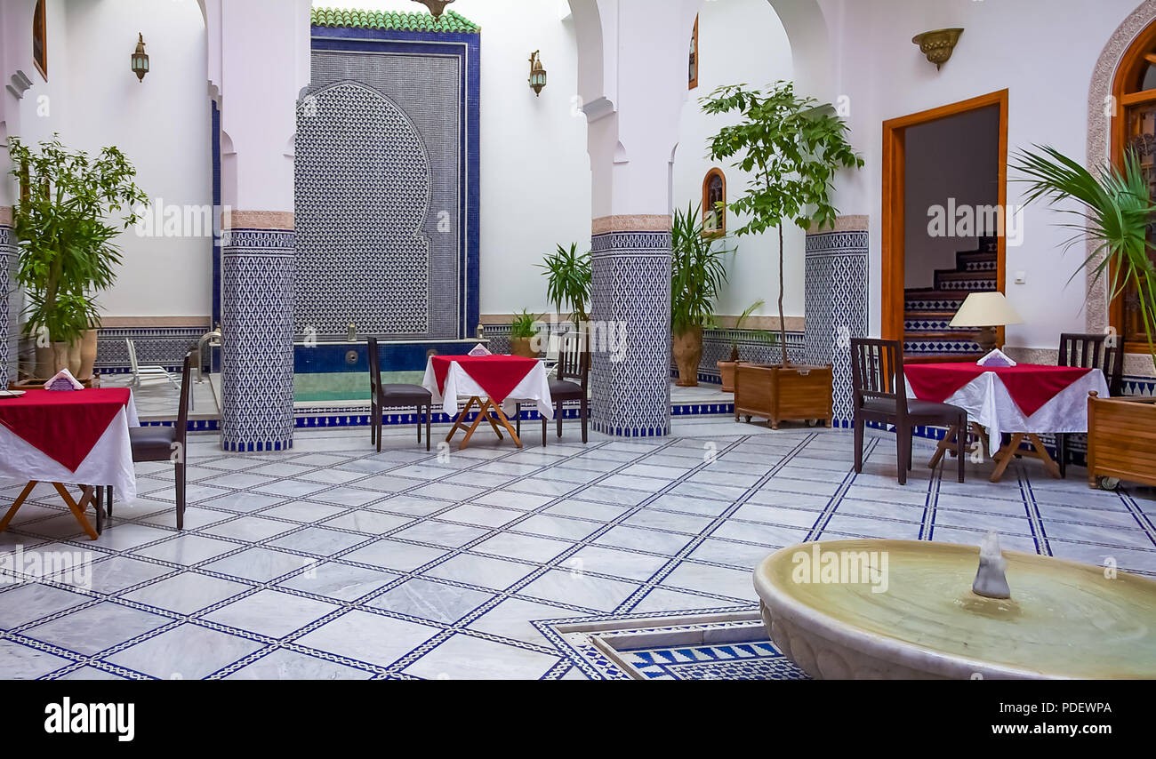 Fes, Maroc - 11 mai 2013 : riad marocain cour intérieure décorée avec des mosaïques et des arcades mauresques mis en place avec des tables et des chaises avec une piscine Banque D'Images