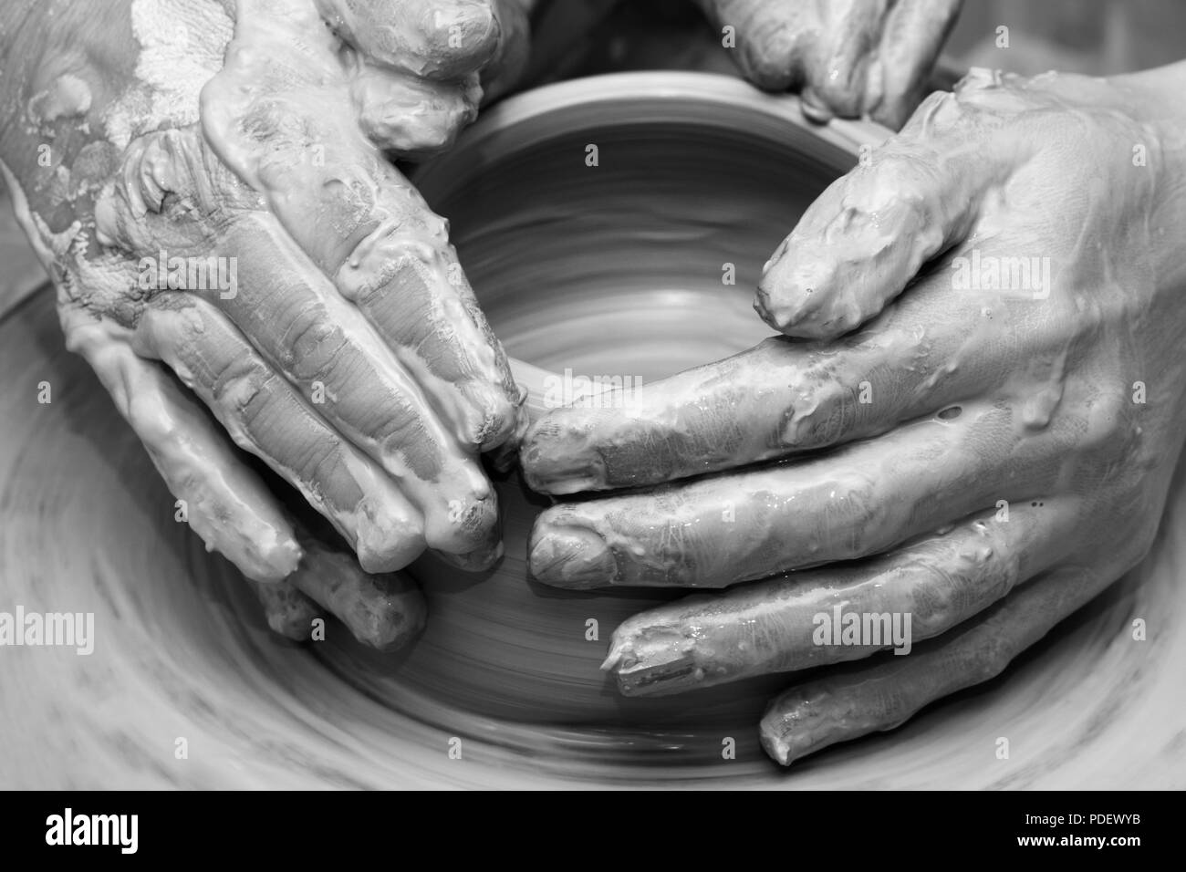 Mains de femmes en argile au processus de fabrication de vaisselle sur les poteries roue. Potter au travail. Vue rapprochée. Image aux tons noir et blanc. Banque D'Images